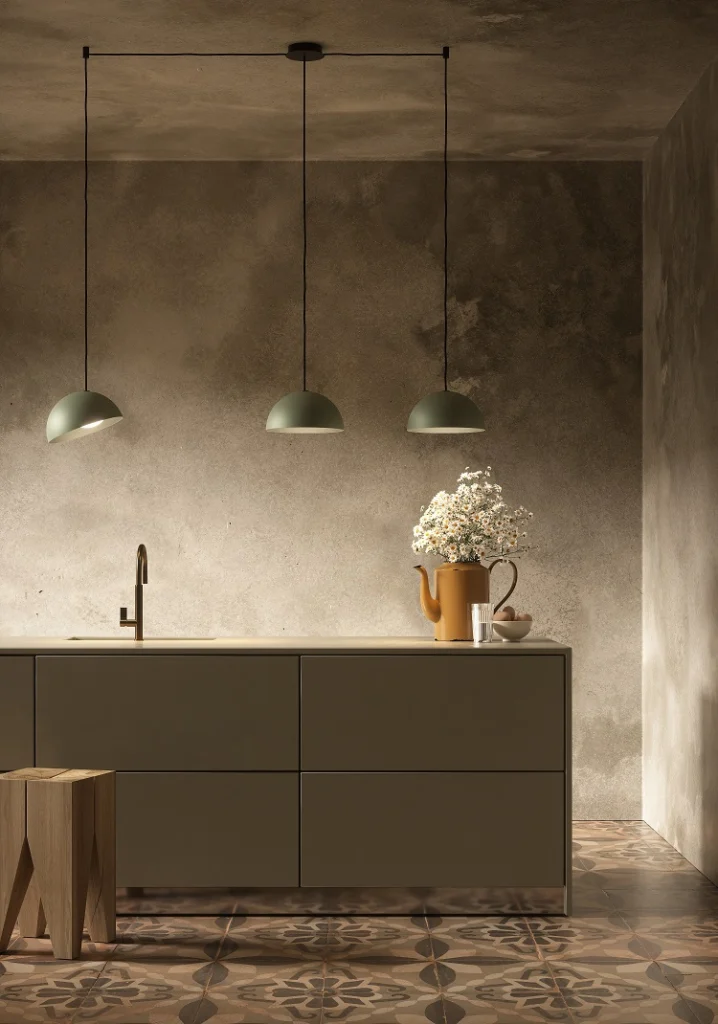 Render di una cucina con tre lampade a sospensione Cini&Nils verde salvia sopra il piano, su parete in cemento