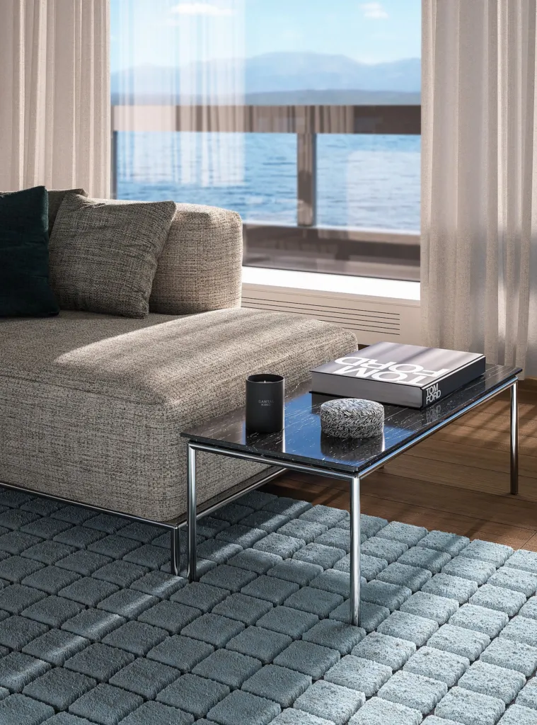 Dettaglio di un divano Cassina e tavolino in vetro con libri su tappeto a quadri