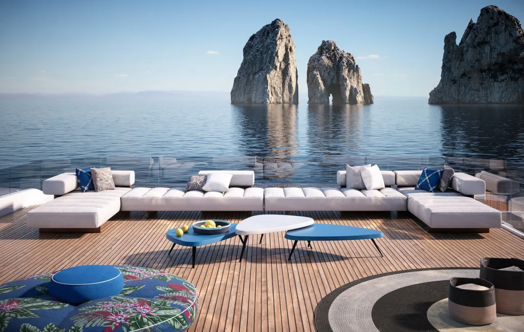 Ponte di uno yacht con divani bianchi Cassina e tappeto colorato davanti ai Faraglioni di Capri