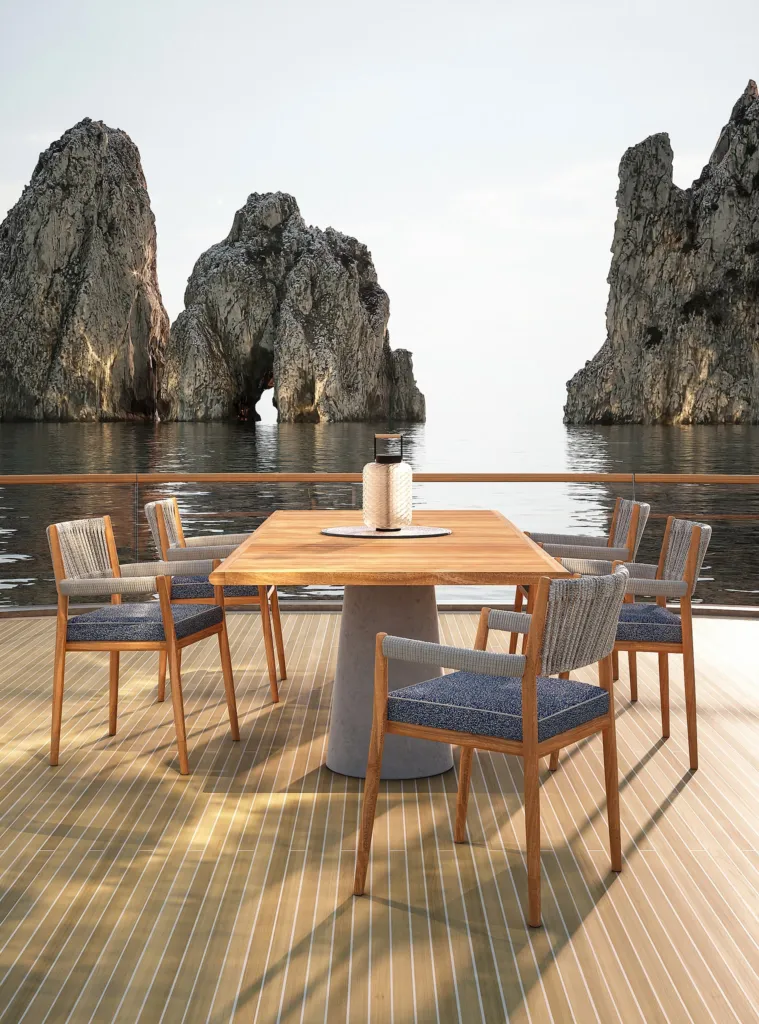 Tavolo e sedie in teak Cassina sul ponte di uno yacht davanti ai Faraglioni di Capri