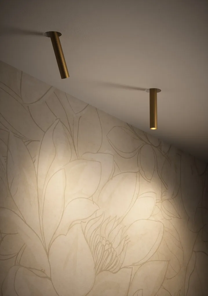 Faretto a soffitto Meno di Cini&Nils che illumina una parete con carta da parati a foglie