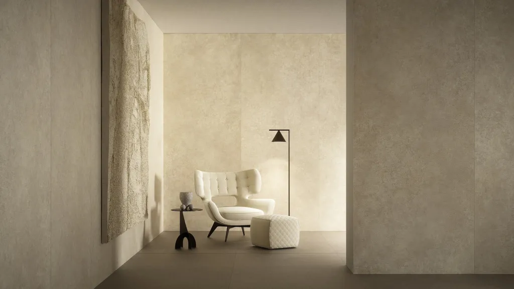 Angolo living con pareti in lastre Laminam effetto pietra chiara e poltrona bianca