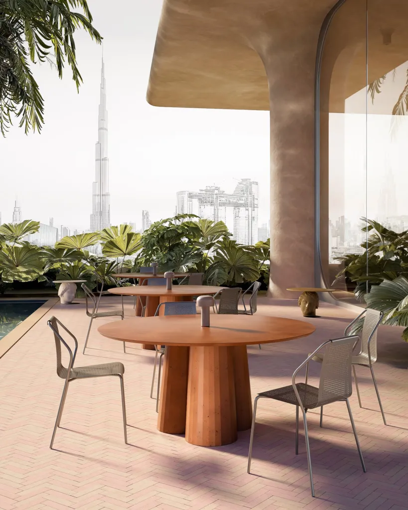 Tavolo rotondo in cemento color terracotta Forma&Cemento su una terrazza con piante a Dubai