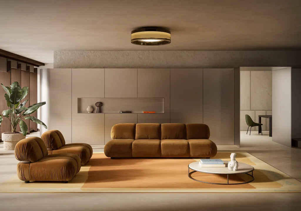 Render di un living Nube con divano modulare e poltrone in velluto color cognac su tappeto ocra