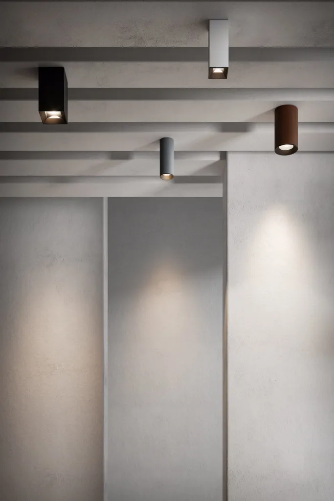 Plafoniere cilindriche Altopiano di Luce&Light in nero, bianco e corten su soffitto in cemento