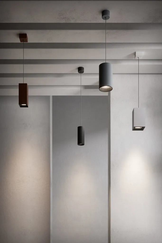Lampade a sospensione cilindriche Altopiano di Luce&Light in diverse finiture su parete in cemento