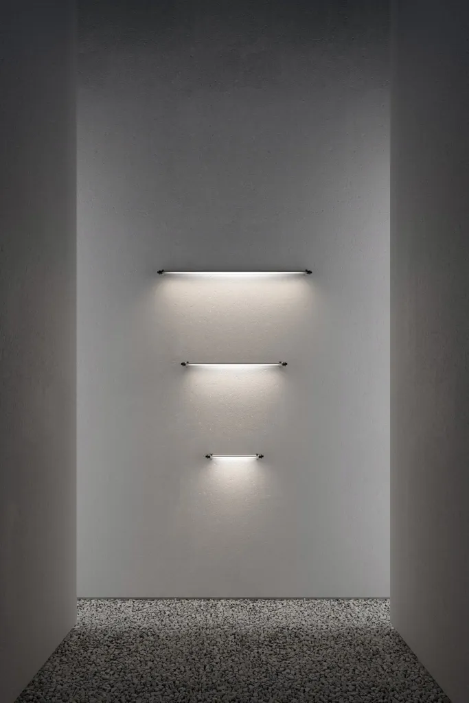 Applique lineari di Luce&Light su una parete chiara sopra un letto di ghiaia