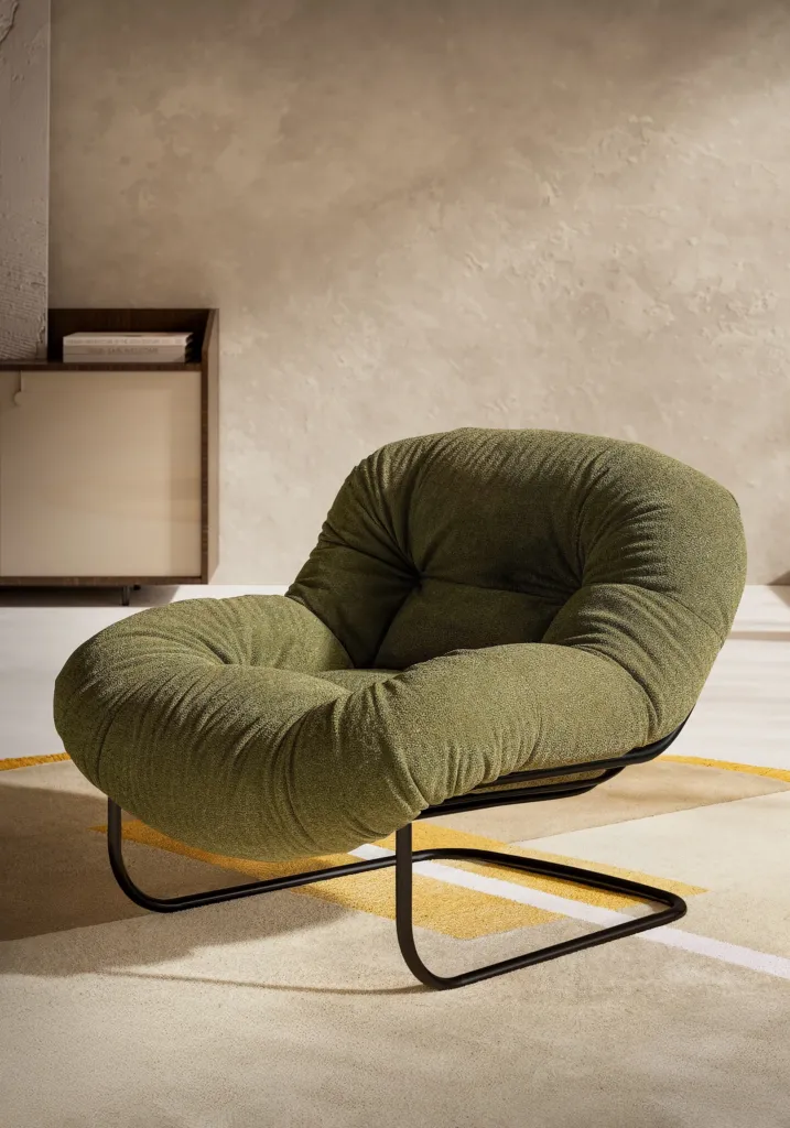 Poltrona imbottita verde con base a slitta in metallo in un ambiente luminoso