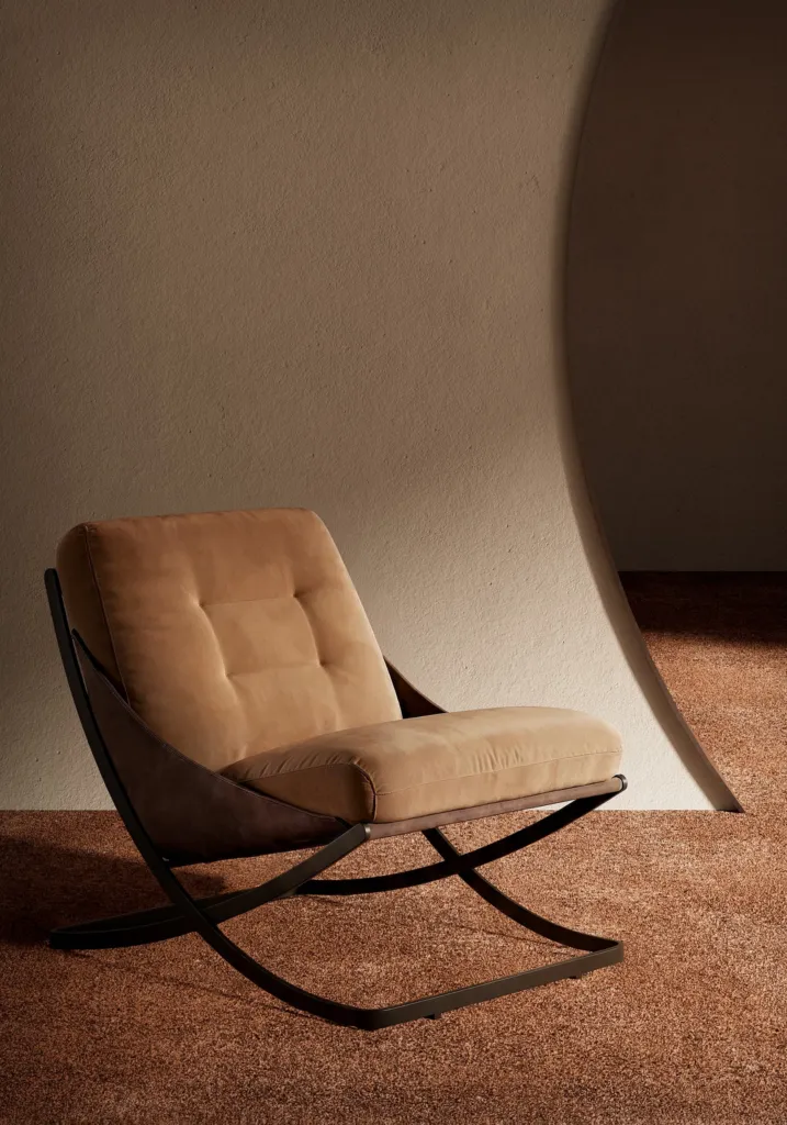 Poltrona con struttura in metallo curvato e cuscini trapuntati color cammello